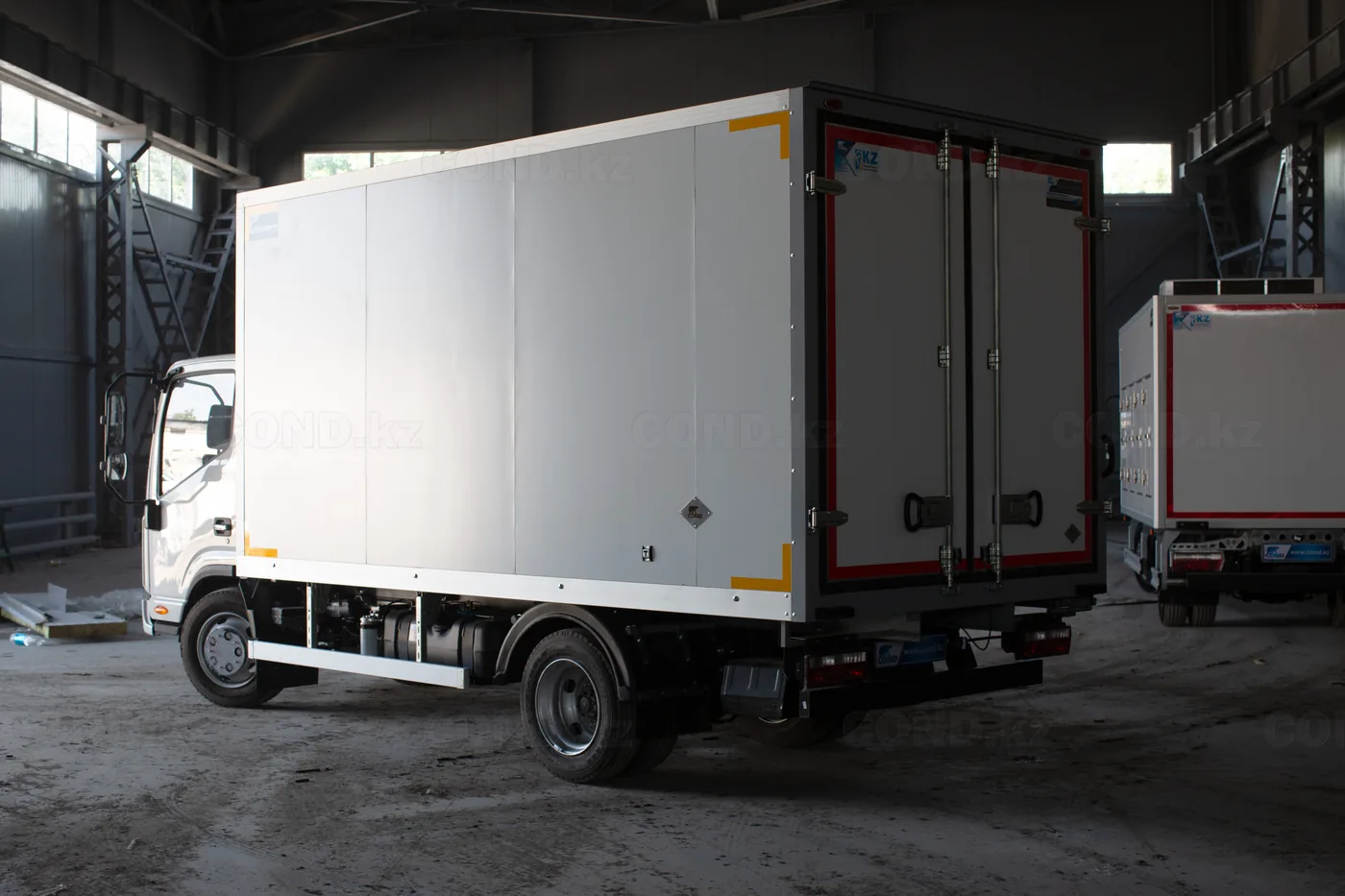 Изотермический фургон COND на шасси JAC N90, вид сбоку в цехе производства в Алматы