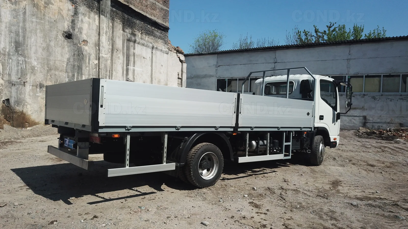 Flatbed body on a JAC N80 chassis — rear three-quarter view, the tailboard and the underrun bar — COND