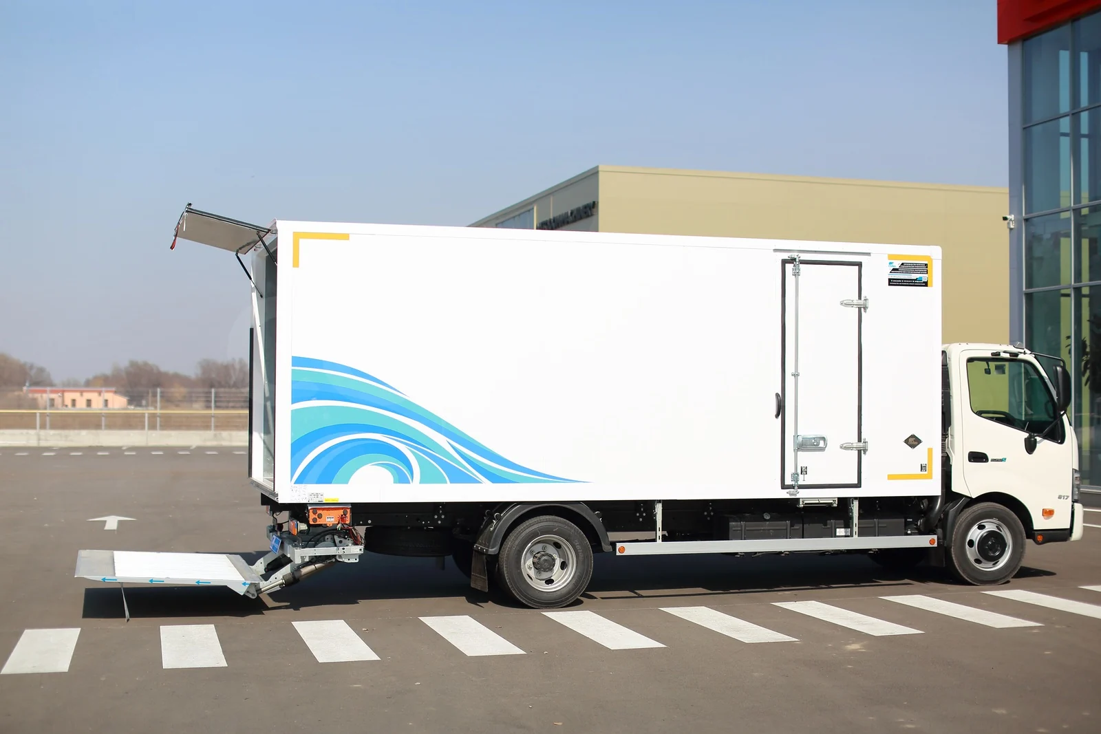 Промтоварный фургон с гидробортом на HINO 300 — вид сбоку: платформа гидроборта опущена к земле — COND