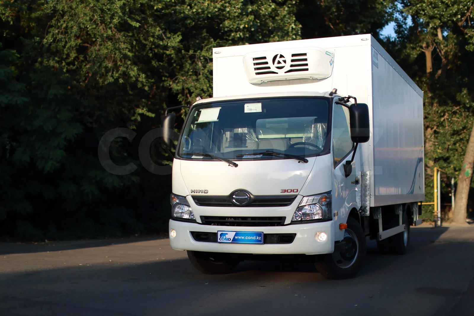 Refrigerated van on a HINO 300 with a strip curtain — front three-quarter view, refrigeration unit over the cab — COND